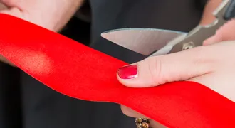 dłonie przecinające nozyczkami czaerwoną wstęgę