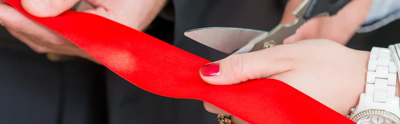 dłonie przecinające nozyczkami czaerwoną wstęgę